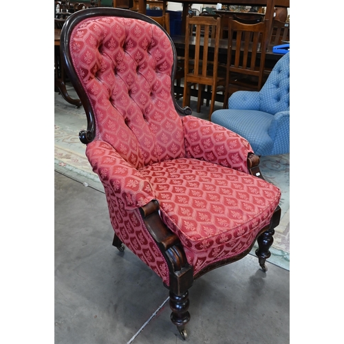 450 - A Victorian mahogany framed button back armchair on turned legs with brass casters