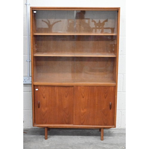 487 - A mid century teak bookcase circa 1960, with sliding glass doors enclosing two adjustable shelves ov... 