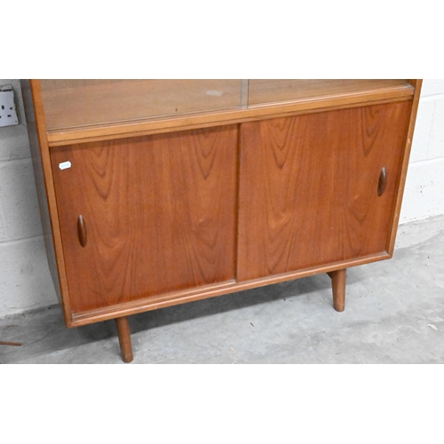 487 - A mid century teak bookcase circa 1960, with sliding glass doors enclosing two adjustable shelves ov... 