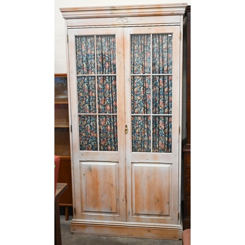 488 - A limewashed pine wardrobe with part glazed and panelled doors enclosing shelf and hanging rail fitt... 