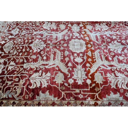 1075 - A contemporary Indian Agra carpet, the red-pink ground with stylised floral design, 323 cm x 242 cm