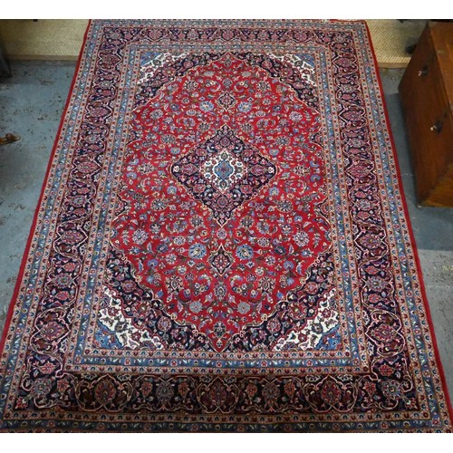 1076 - A Persian Kashan red ground carpet, with traditional stylised floral design, 348 cm x 248 cm