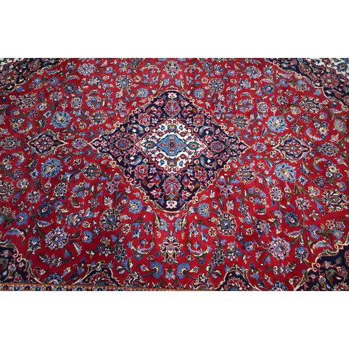 1076 - A Persian Kashan red ground carpet, with traditional stylised floral design, 348 cm x 248 cm