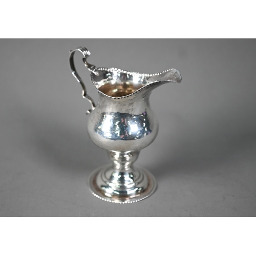 129 - Hester Bateman: a silver baluster cream jug with impressed beaded rim, scroll handle and stemmed cir... 