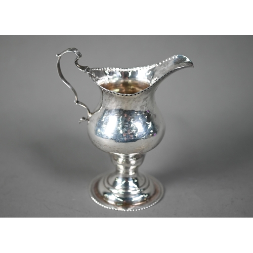 129 - Hester Bateman: a silver baluster cream jug with impressed beaded rim, scroll handle and stemmed cir... 