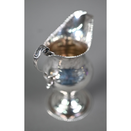 129 - Hester Bateman: a silver baluster cream jug with impressed beaded rim, scroll handle and stemmed cir... 