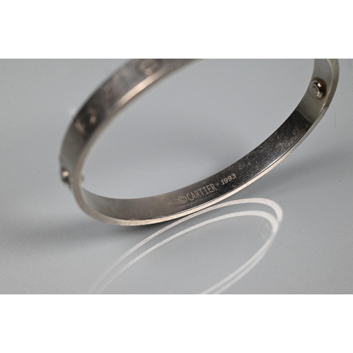 335 - Cartier - an oval 'love' bangle, white metal stamped 750, etched Cartier inscription numbered M.1653... 