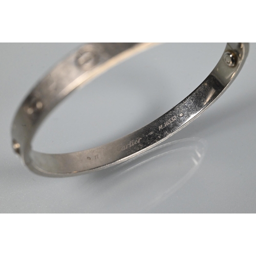 335 - Cartier - an oval 'love' bangle, white metal stamped 750, etched Cartier inscription numbered M.1653... 