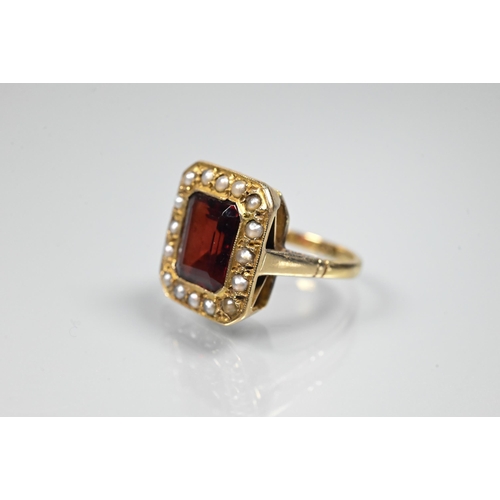 356 - A yellow metal ring of rectangular design featuring emerald-cut red stone, probably garnet, surround... 