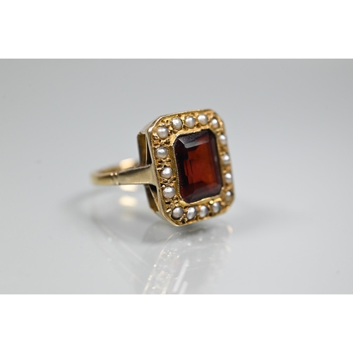 356 - A yellow metal ring of rectangular design featuring emerald-cut red stone, probably garnet, surround... 