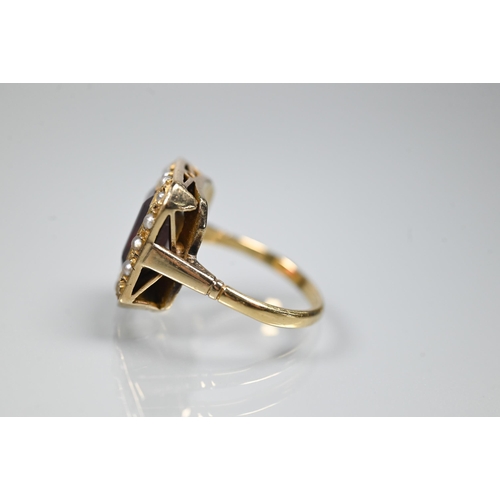 356 - A yellow metal ring of rectangular design featuring emerald-cut red stone, probably garnet, surround... 