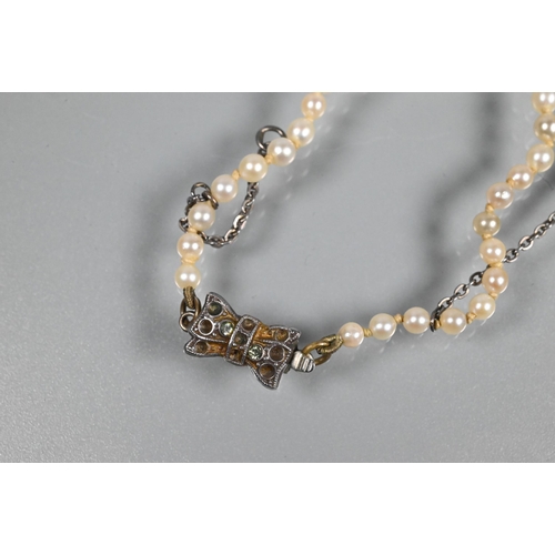 358 - A graduated row of cultured pearls double knotted throughout onto white metal snap in the form of a ... 