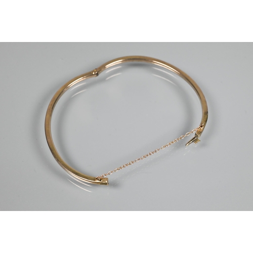 362 - A narrow oval half hinged bangle fitted with safety chain, unmarked and untested, approx 4.9g