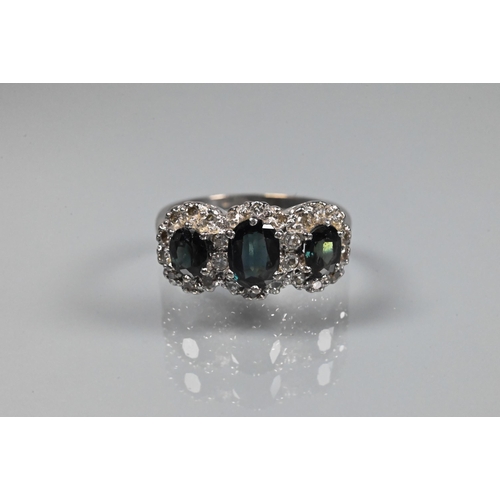 369 - A three stone cluster ring, the three oval stones (possibly sapphire?) of green/blue hue surrounded ... 