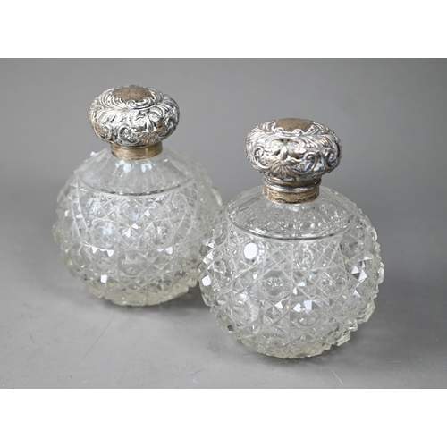 77 - A pair of Edwardian hobnail-cut globular cologne bottles, the hinged silver bun covers with embossed... 