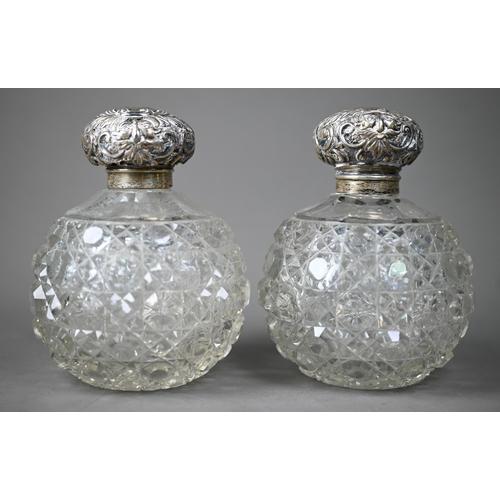 77 - A pair of Edwardian hobnail-cut globular cologne bottles, the hinged silver bun covers with embossed... 