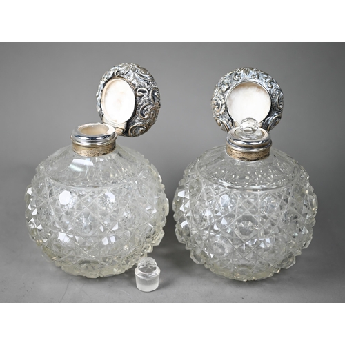 77 - A pair of Edwardian hobnail-cut globular cologne bottles, the hinged silver bun covers with embossed... 