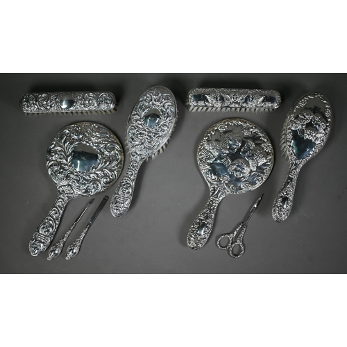 235 - An embossed silver five-piece brush set with hand-mirror, Birmingham 1985, to/w another hand-mirror,... 