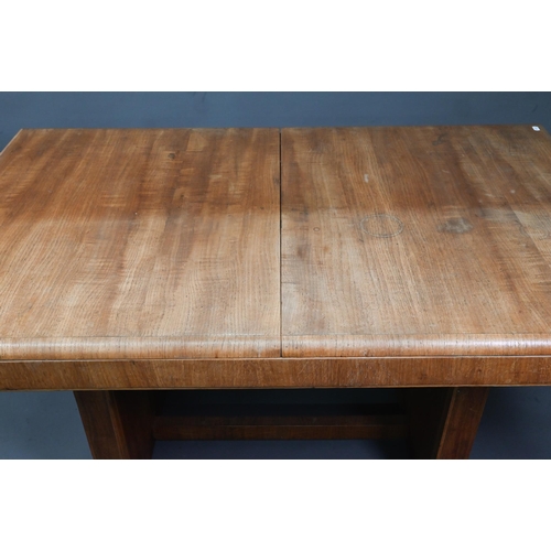 1021 - An Art Deco oak draw-leaf dining table, the top with integral folding central leaf, raised on slab e... 