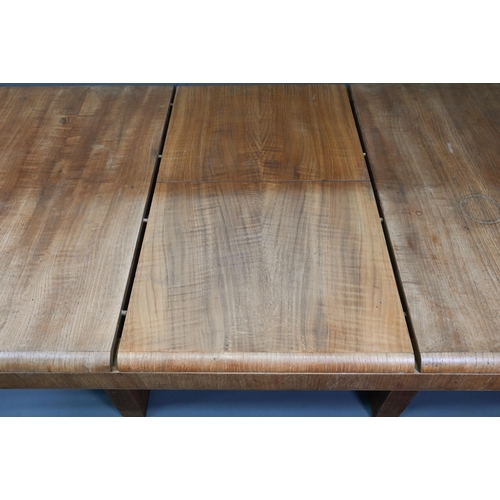 1021 - An Art Deco oak draw-leaf dining table, the top with integral folding central leaf, raised on slab e... 