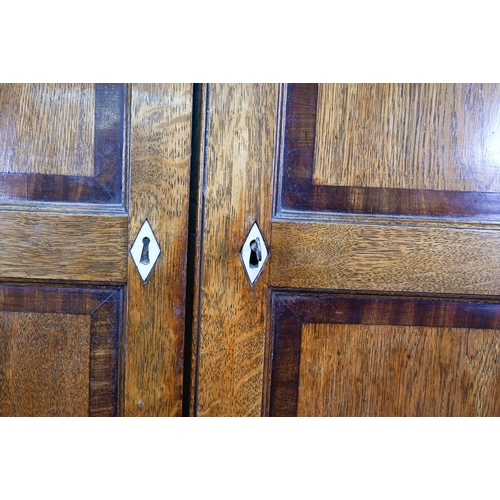 1028 - A Georgian oak corner cupboard, in two parts, the upper with broken swan-neck pediment over a pair o... 