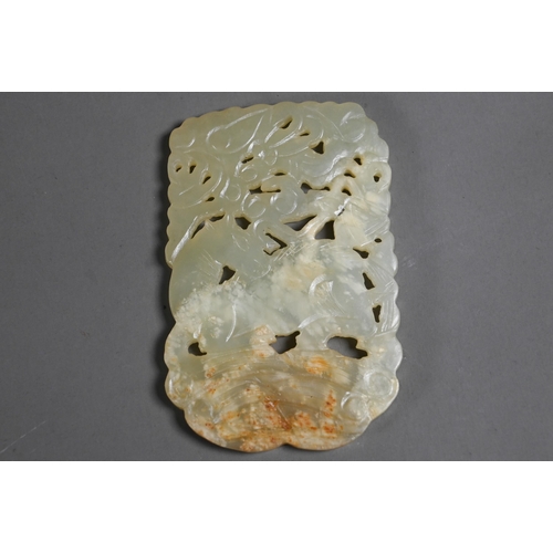 515 - A Chinese jade amulet or pendant, the pale celadon stone with white and russet inclusions intricatel... 