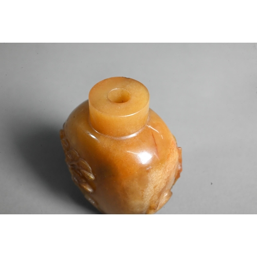 544 - A Chinese butterscotch agate snuff bottle, carved in relief with a sage, deer, crane and pine tree -... 