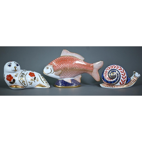 628 - Two Royal Crown Derby figures, snail and Fish, to/w three paperweights with silver plugs: Frog, Seal... 