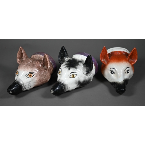 632 - Two early 19th century Pratt-type pottery fox's head stirrup cups with pink lustre collars, to/w a s... 