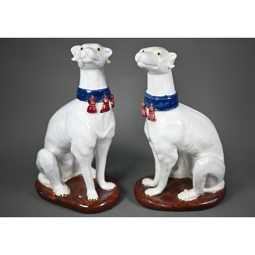 A pair of 20th century glazed terracotta heraldic seated talbots with tasselled collars, on oval bases, 35 cm high (2)