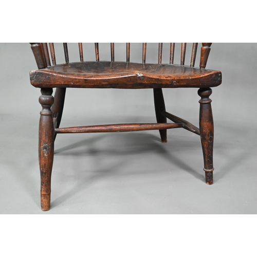 902 - An antique elm seat comb-back chair, raised on turned legs united by an H-stretcher