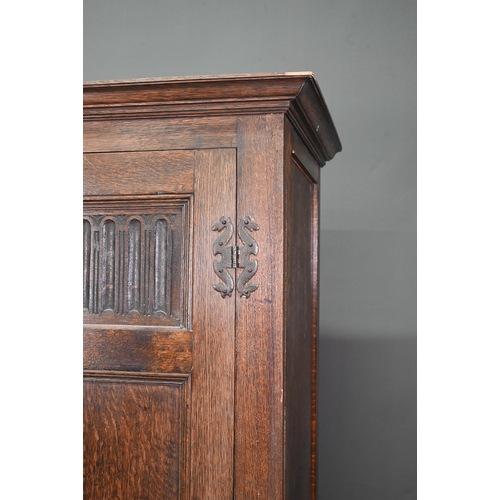 923 - A 17th century style oak wardrobe, the twin doors with part linenfold moulded panels, on block feet,... 