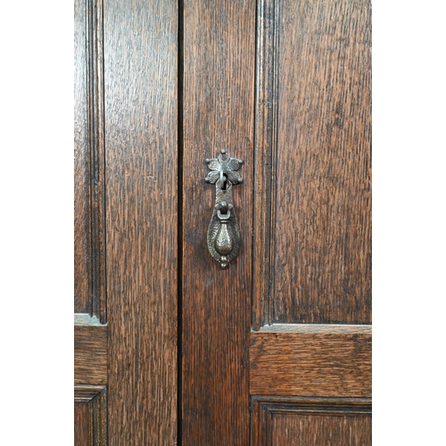 923 - A 17th century style oak wardrobe, the twin doors with part linenfold moulded panels, on block feet,... 