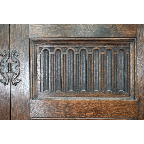 923 - A 17th century style oak wardrobe, the twin doors with part linenfold moulded panels, on block feet,... 