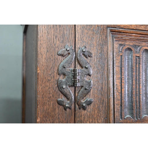 923 - A 17th century style oak wardrobe, the twin doors with part linenfold moulded panels, on block feet,... 