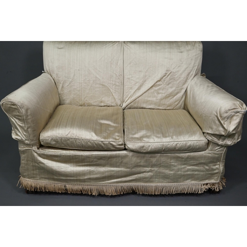 963 - A traditional two-seat sofa with gold silk loose covers over patterned undercloth, raised on hip car... 