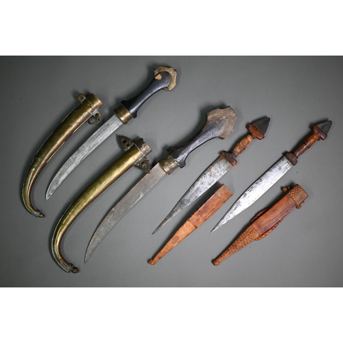 1319 - Two old chased brass mounted Eastern daggers, with curved steel 23 cm blades, with shaped wooden gri... 