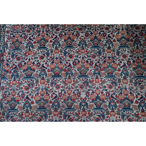 1068 - An antique Persian Qom rug, repeating floral vase design on camel ground, 220 cm x 138 cm