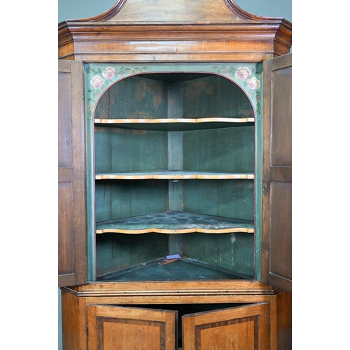 1028 - A Georgian oak corner cupboard, in two parts, the upper with broken swan-neck pediment over a pair o... 