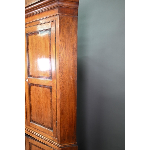 1028 - A Georgian oak corner cupboard, in two parts, the upper with broken swan-neck pediment over a pair o... 