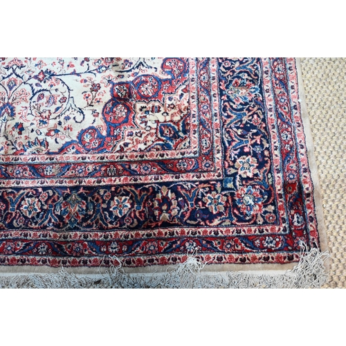 1066 - A fine Persian handmade Kashan carpet, the floral vine design on cream ground centred by a blue grou... 