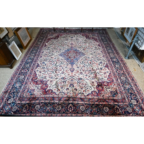 A fine Persian handmade Kashan carpet, the floral vine design on cream ground centred by a blue ground medallion, 360 cm x 266 cm