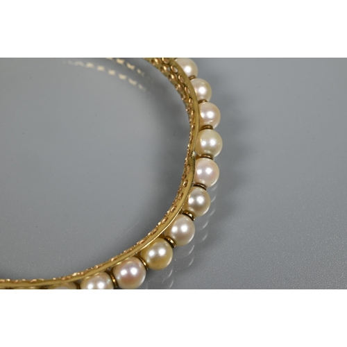 344 - A yellow metal pearl-set bangle, the pierced open grill core set with thirty-one cultured pearls wit... 