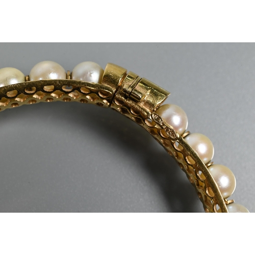 344 - A yellow metal pearl-set bangle, the pierced open grill core set with thirty-one cultured pearls wit... 