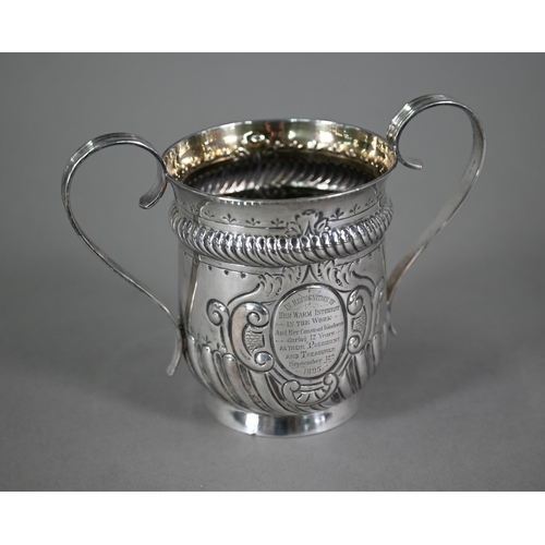 135 - A late Victorian loving cup in the Carolean manner, with reeded strap handles and embossed decoratio... 