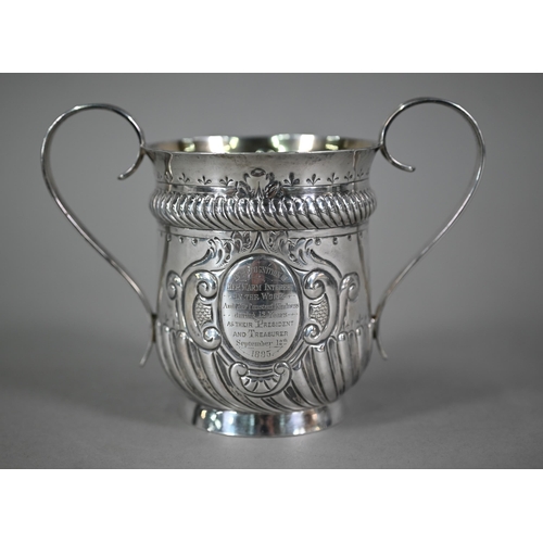 135 - A late Victorian loving cup in the Carolean manner, with reeded strap handles and embossed decoratio... 