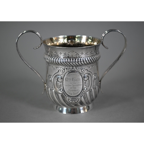 135 - A late Victorian loving cup in the Carolean manner, with reeded strap handles and embossed decoratio... 