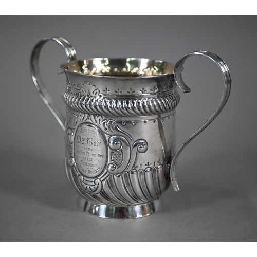 135 - A late Victorian loving cup in the Carolean manner, with reeded strap handles and embossed decoratio... 