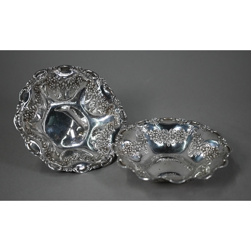 140 - An Edwardian pair of silver dishes with dimpled sides, scrolling rims and embossed and chased floral... 