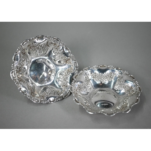 140 - An Edwardian pair of silver dishes with dimpled sides, scrolling rims and embossed and chased floral... 